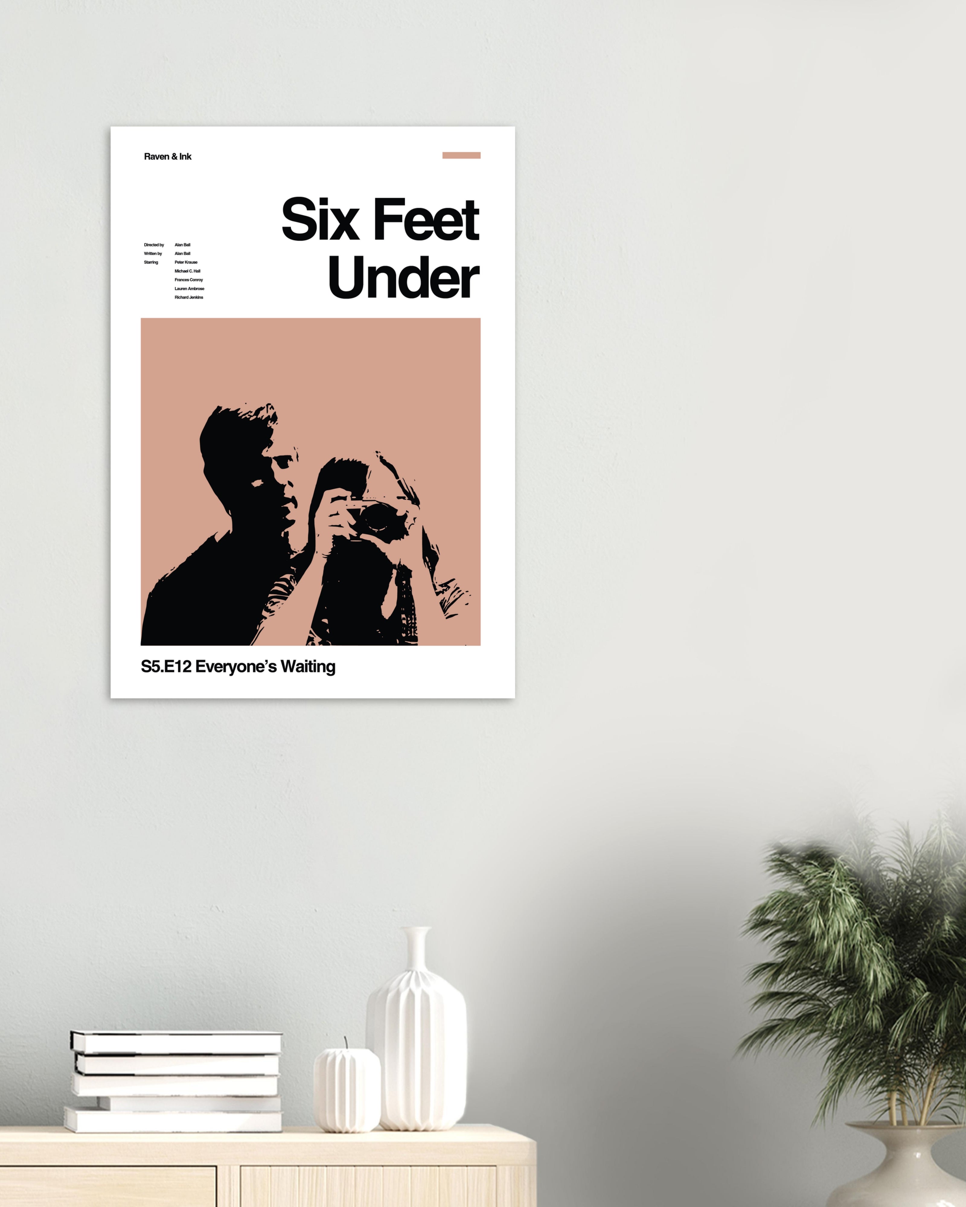 Six Feet Under poster on a wall in a light living room with decor below.